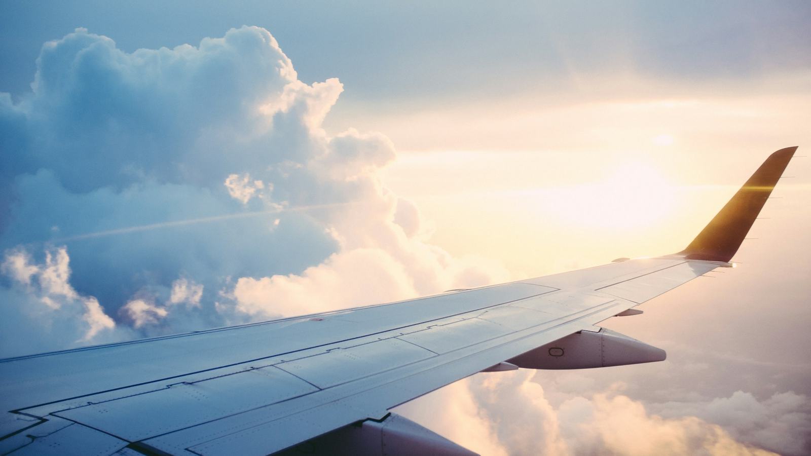 Airliner wing above clouds in warm sunlight