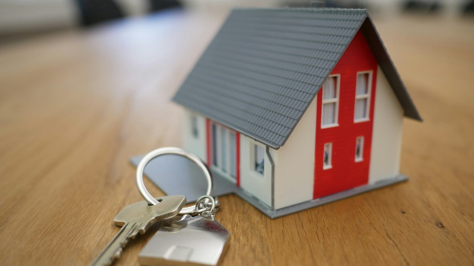 Keys beside a small building model on a wooden table