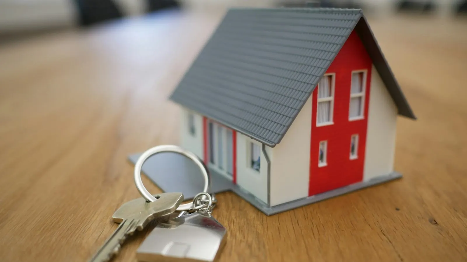 Keys beside a small building model on a wooden table