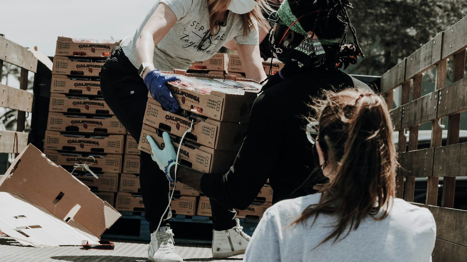 Relief volunteers in masks unloading supply boxes from a truck