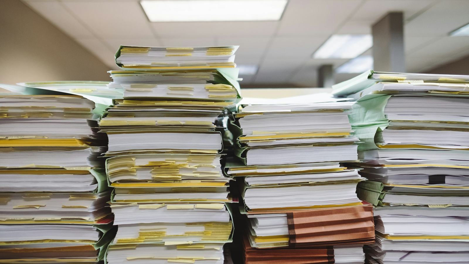 Tall stacks of billing files and invoices awaiting reconciliation