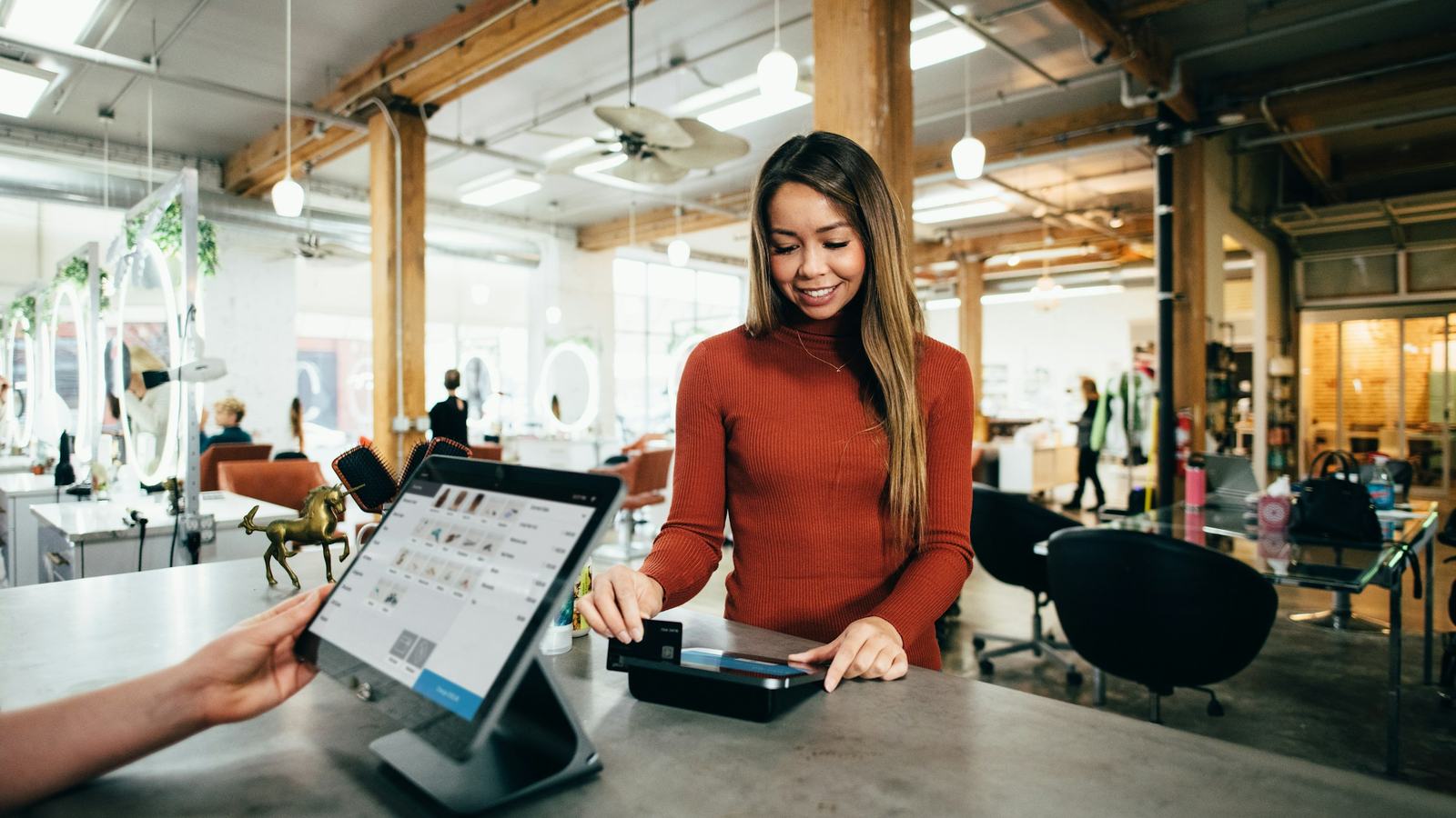 Guest paying by card at a counter terminal while staff use a tablet