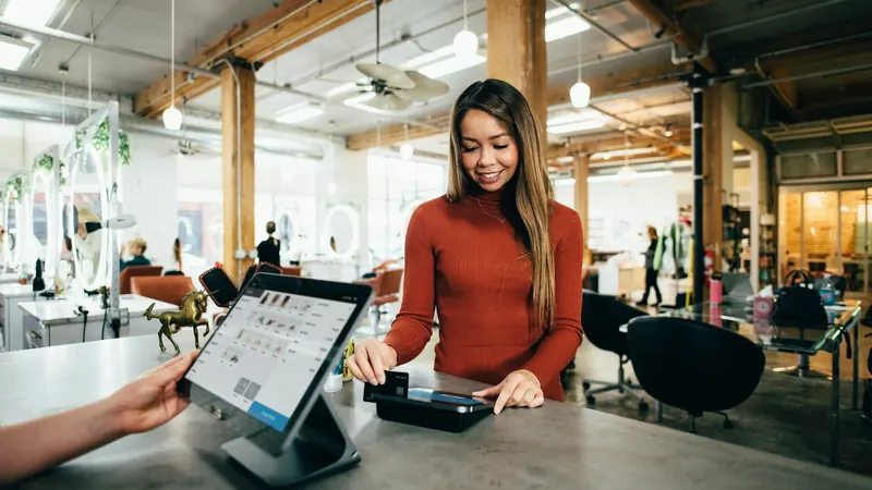 Guest paying by card at a counter terminal while staff use a tablet