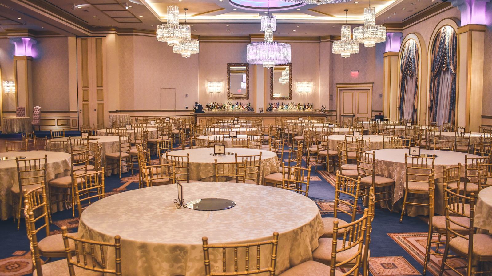 Hotel ballroom set with round banquet tables and chandeliers for a group event