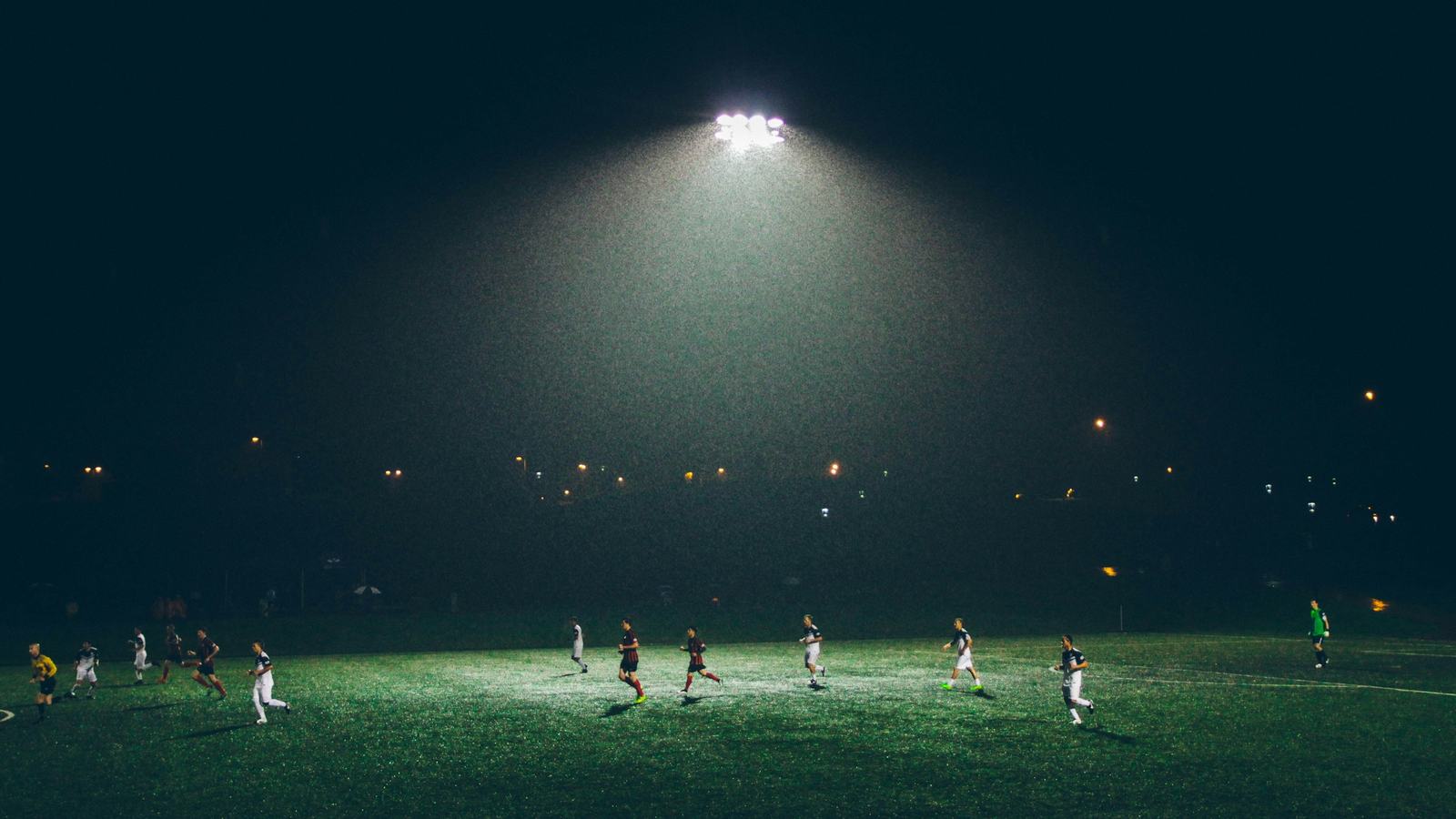 Amateur soccer match under stadium lights on a night field