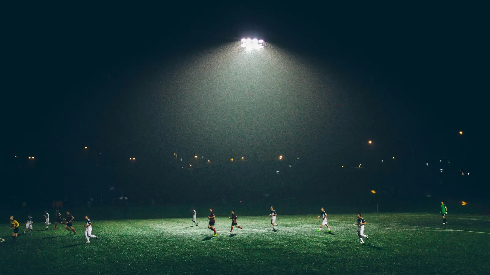 Amateur soccer match under stadium lights on a night field