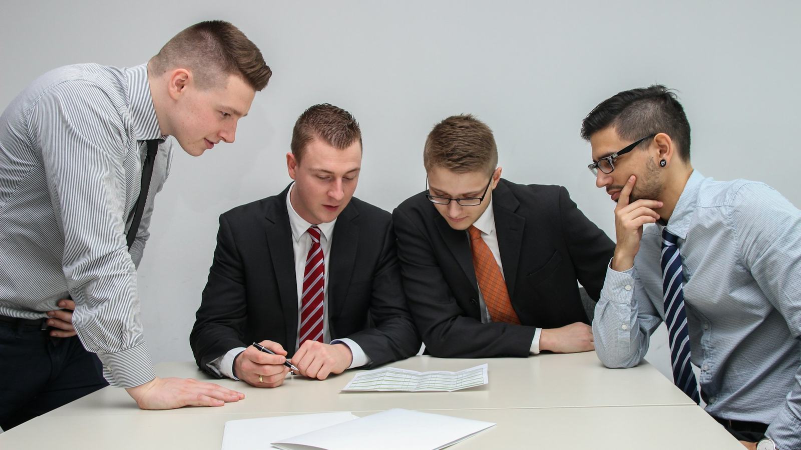 Four professionals in business attire reviewing papers at a table