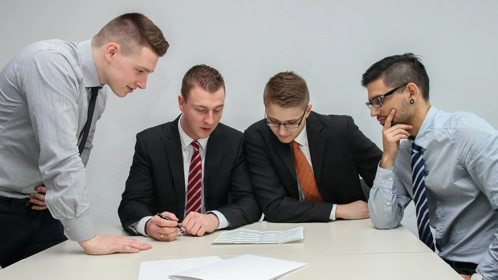 Four professionals in business attire reviewing papers at a table