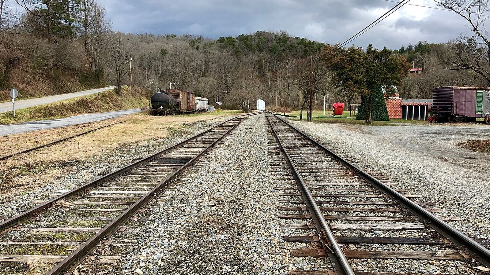 Freight rail yard tracks with tank and box cars under a cloudy sky